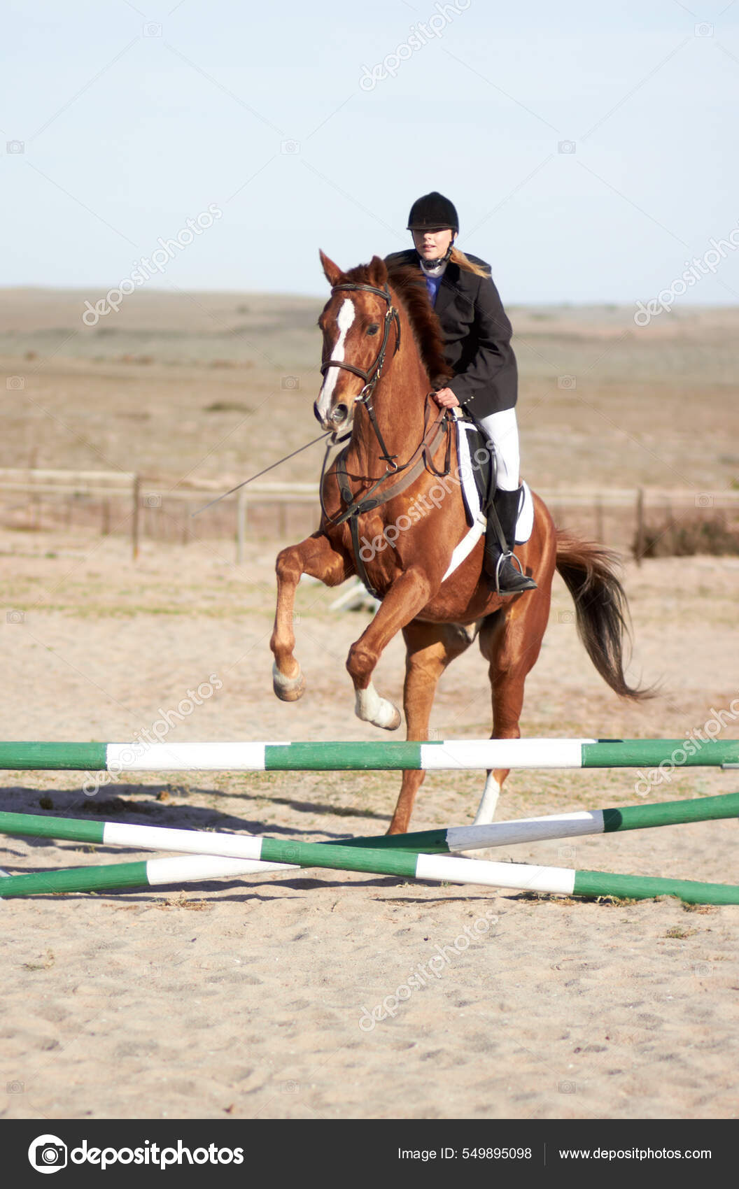 Há uma mulher montando um cavalo pulando sobre um obstáculo