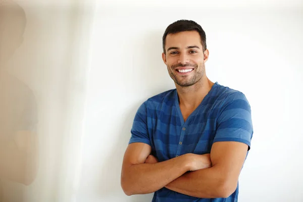 Voller Positivität. Ein gutaussehender junger Mann lächelt, während er mit verschränkten Armen steht. — Stockfoto