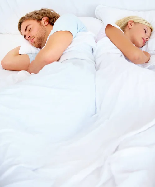 Im Widerspruch zueinander. Ein junges Paar schläft zurück ins Bett. — Stockfoto