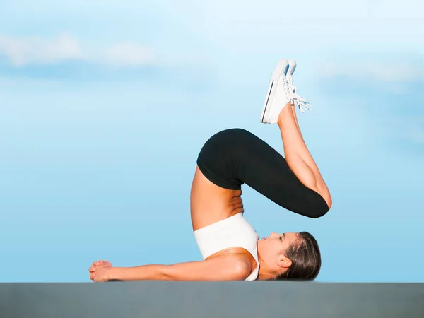 Em controlo total do corpo dela. Uma jovem mulher fazendo ioga ao ar livre contra um céu azul. — Fotografia de Stock