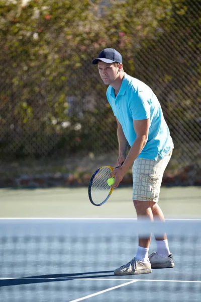 Han ska servera en stinger. En fokuserad ung man gör sig redo att tjäna på tennisbanan. — Stockfoto