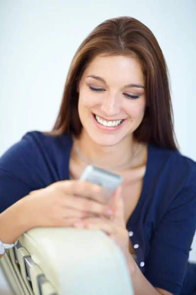 Godendo di un testo umoristico da un amico. Una bella giovane donna che manda un messaggio dal suo cellulare. — Foto Stock