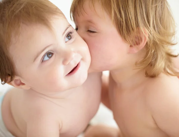 Det finns ingen rivalitet mellan syskonen. Närbild av en söt liten flicka som ger sin lillasyster en kyss på kinden. — Stockfoto