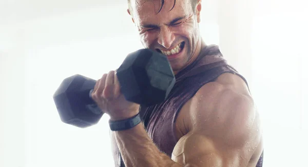 Unleash that inner beast. Shot of a muscular young man lifting weights in a gym. — Stock Photo, Image