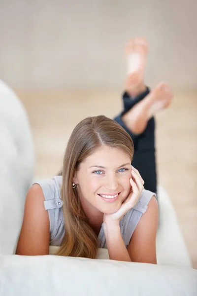 Avkopplande ung skönhet. Söt ung kvinna som kopplar av i soffan med ett sött leende - porträtt. — Stockfoto