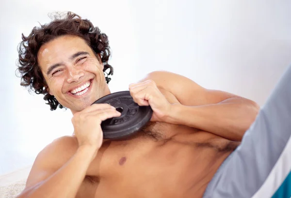 Añadir peso aumenta la resistencia. Un joven sexy haciendo sesiones con un peso en el suelo. —  Fotos de Stock