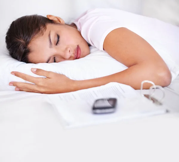 Iedereen heeft meer slaap nodig. Shot van een aantrekkelijke vrouw slapend op haar bed met haar mobiele telefoon en papierwerk naast hier. — Stockfoto