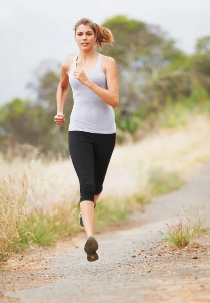 Løper etter trening. En ung kvinne på en grusvei.. – stockfoto