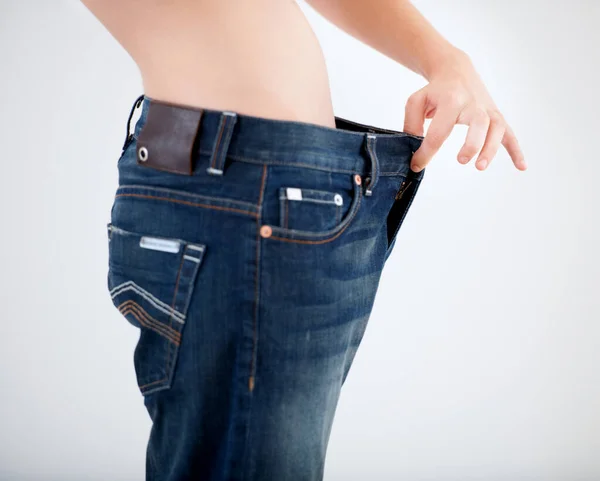 Cambiar su dieta le ha funcionado. Imagen recortada de una mujer tirando de la cintura de sus pantalones - Pérdida de peso. — Foto de Stock
