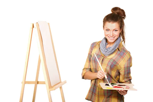 The creative juices are about to flow.... Studio shot of a young woman holding a palette and brush and standing with an easel. — Stock Photo, Image