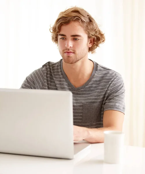 Genieten van het internet op zijn vrije dag. Een jongeman die thuis zijn laptop gebruikt. — Stockfoto