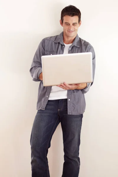 Accediendo a Internet desde cualquier lugar. Un joven guapo trabajando en su portátil. — Foto de Stock