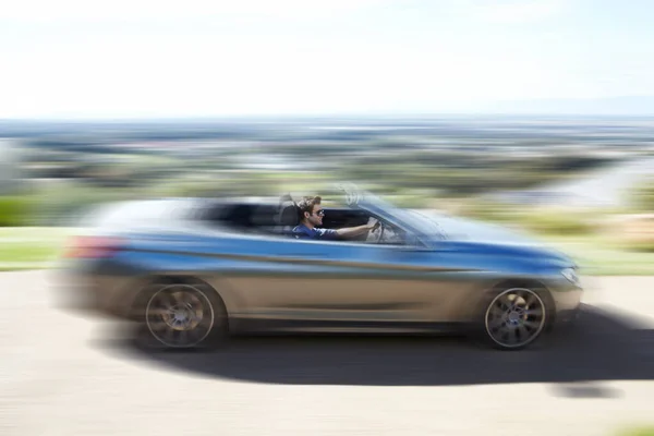 Han är ett speedfreak. En ung man kör fortare på den öppna vägen i sitt silverbord.. — Stockfoto