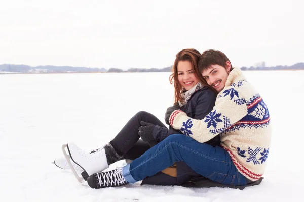 Wir lieben diese Zeit des Jahres. Süßes junges Paar auf Schlittschuhen kuschelt auf dem Eis eines zugefrorenen Natursees im Freien. — Stockfoto