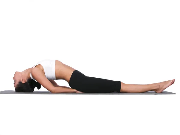Allungando la parte bassa della schiena. Una giovane donna che fa stretching mentre è isolata sul bianco. — Foto Stock