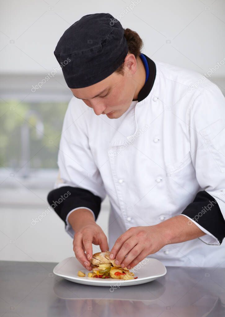 Creating a culinary masterpiece. Young chef preparing a chicken dish in a kitchen - Fine Dining.