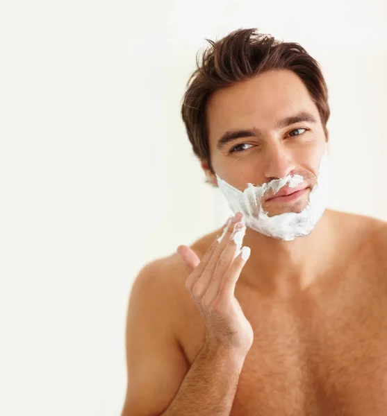 Un joven que se aplica crema en la cara para afeitarse. Retrato de un joven guapo que se aplica crema en la cara para afeitarse. —  Fotos de Stock