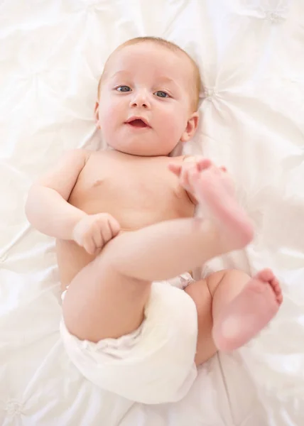 Theres a big wide world to explore.... Cute little baby lying down and touching its feet. — Stock Photo, Image