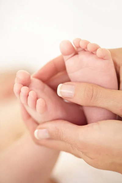 Vagga små fötter. Beskuren närbild av en mor som håller sina barn fötter. — Stockfoto