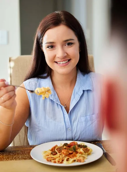 私が愛する料理を食べることは私の一日のハイライトです。家で食べるために座っている若い女性のショット. — ストック写真