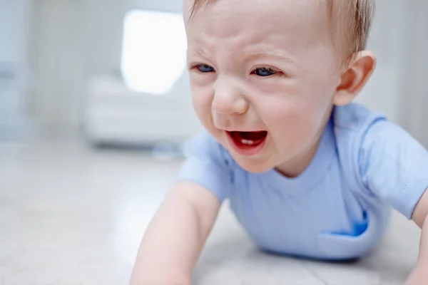 La dentizione non è divertente. Primo piano di un bambino molto infelice sdraiato sul pavimento. — Foto Stock