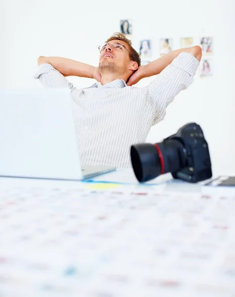 Fotograf entspannt. Fotograf mit Laptop und entspannt mit den Händen hinter dem Kopf. — Stockfoto