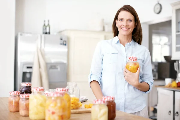 Счастливо работать на кухне. Портрет зрелой женщины, стоящей с банкой на кухне. — стоковое фото