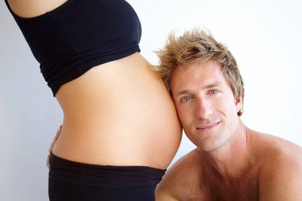 Partager un moment spécial. beau jeune père pour être à l'écoute de son enceinte femmeamp039s ventre. — Photo