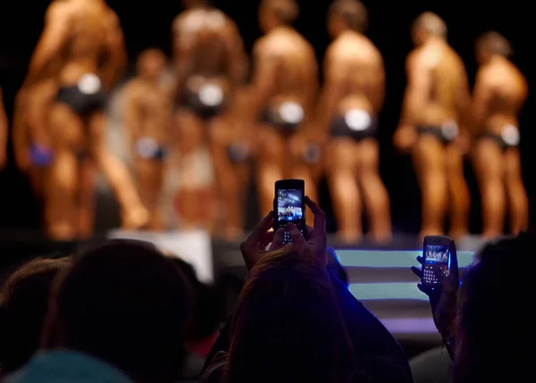 Apanhar os seus favoritos na câmara. O público de uma competição de musculação tirando fotos dos concorrentes com seus celulares. — Fotografia de Stock