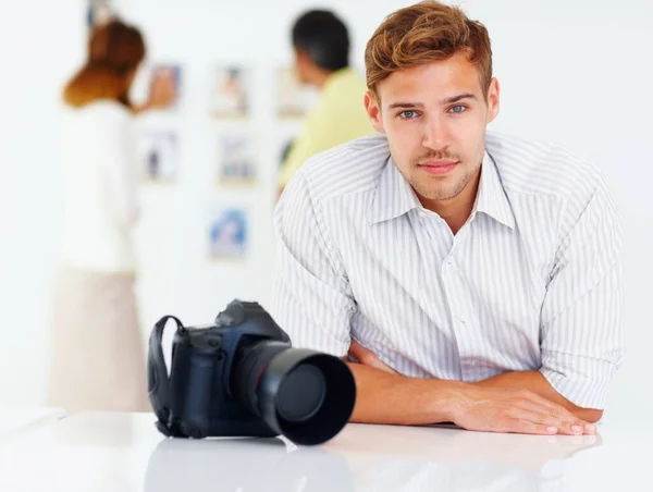 Fotograf am Tisch. Porträt eines Fotografen, der am Tisch sitzt und sich die Bilder im Hintergrund ansieht. — Stockfoto