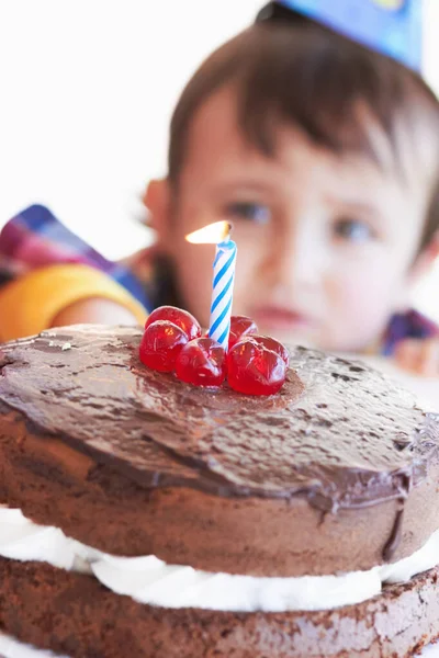 Celebrating a special day. A birthday cake with one candle with the birthday boy in the background. — Stock Photo, Image