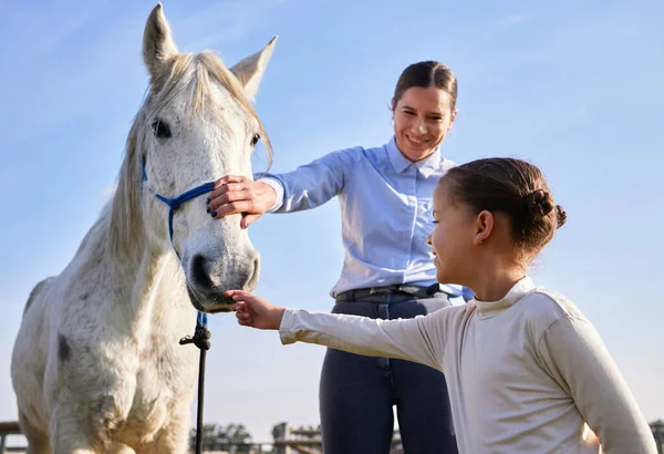 Juste comme ça. Coupé plan d'une jolie jeune femme et sa fille caressant un cheval à l'extérieur sur le ranch. — Photo