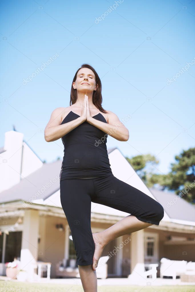 Focused on finding peace. An attractive woman practicing yoga outside with her hands in prayer positon.