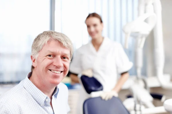 和助手一起微笑的医生英俊的牙医和他的助手在办公室里笑的画像. — 图库照片