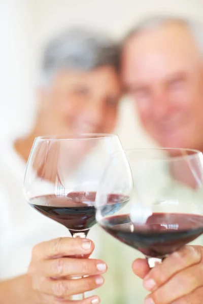 Volwassen koppel toasten op rode wijn. Portret van volwassen stel vieren met toast, focus op wijnglazen. — Stockfoto