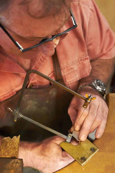 慎重に形を切り取る-ジュエリー製造。金細工師の上から見た金属片. — ストック写真