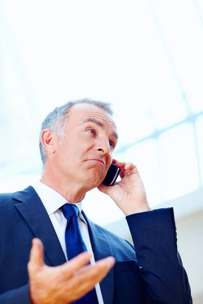 Executivo parecendo incerto ao telefone. Executivo sênior com olhar confuso enquanto no telefone celular. — Fotografia de Stock