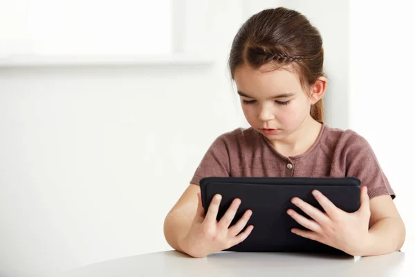 Digitális kor minden korosztály számára. Egy imádnivaló kislányról, aki digitális táblát olvas.. — Stock Fotó