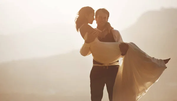 Günbatımı romantizmi. Bir damat gelinini taşıyor.. — Stok fotoğraf