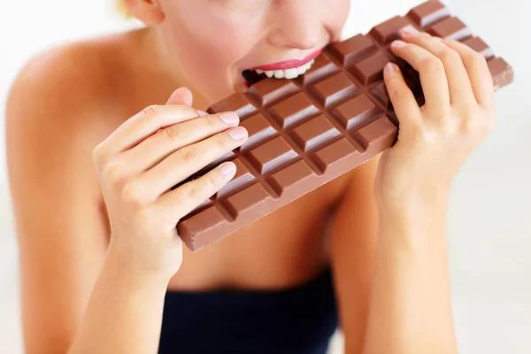 Nada além de indulgência pecaminosa. Vista cortada de uma jovem mordendo em uma grande laje de chocolate. — Fotografia de Stock