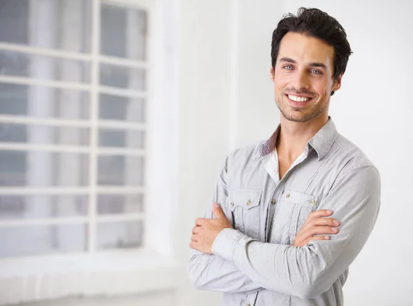 Vertrouwen is besmettelijk. Portret van een lachende knappe man met gekruiste armen. — Stockfoto