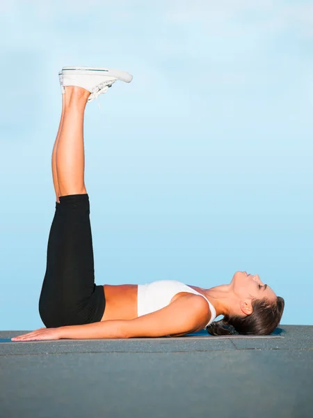 Allungare quei tendini del ginocchio. Una giovane donna che fa yoga all'aperto contro un cielo blu. — Foto Stock