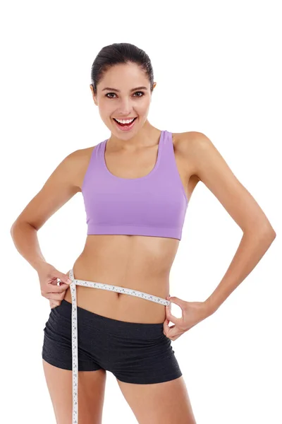 Slimming down for summer. Three quarter length shot of an attractive young woman in gym clothes measuring her waist. — Stock Photo, Image