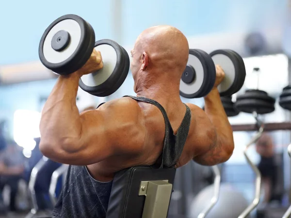 Hij drong zich op. Opname van een mannelijke bodybuilder tillen gewichten in de sportschool. — Stockfoto
