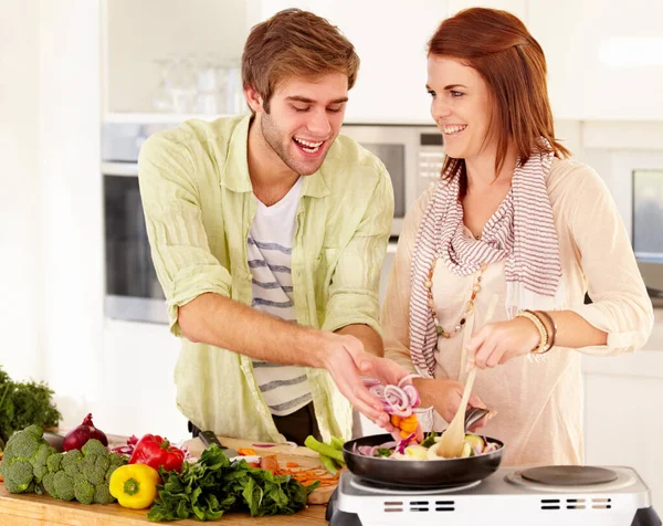 Ele adora cozinhar. Um jovem casal cozinhar na cozinha. — Fotografia de Stock