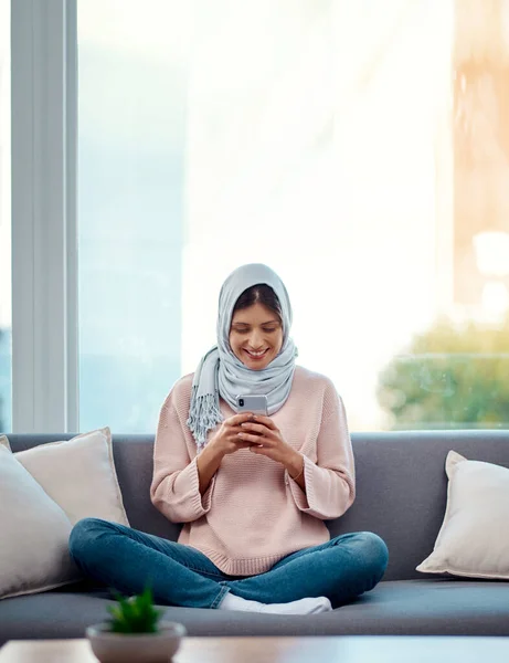 C'est le week-end. Il est temps de faire des plans. Plan complet d'une jolie jeune femme envoyant un texte tout en se refroidissant sur son canapé à la maison. — Photo