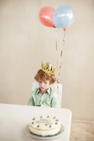 Belki herkes doğum günümü unutmuştur. Doğum günü pastasıyla masada otururken mutsuz görünen küçük şirin bir çocuğun fotoğrafı.. — Stok fotoğraf