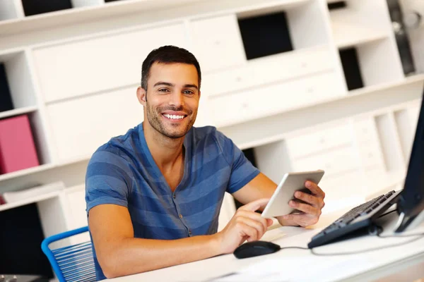 他的生意受到他的触摸屏的推动.一位面带微笑的年轻企业家在他的数码平板电脑上工作. — 图库照片