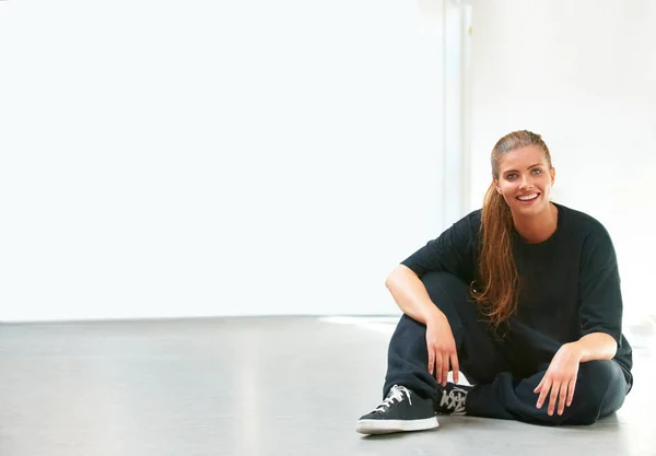 Eine Pause vom zeitgenössischen Tanz. Eine schöne junge Frau sitzt auf dem Boden ihres Tanzstudios. — Stockfoto