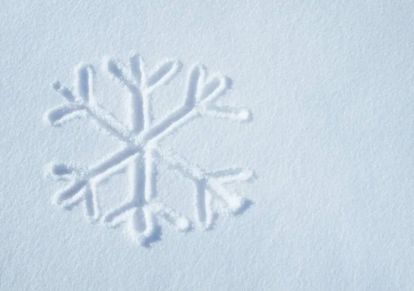 La neige a commencé à tomber. Vue d'un symbole de flocon de neige sur une surface de neige. — Photo